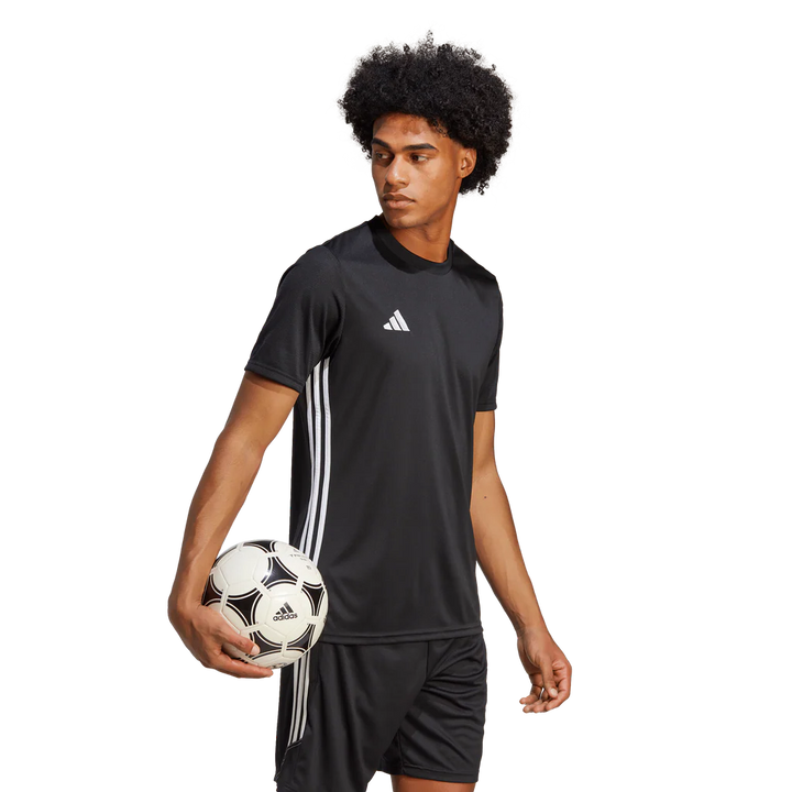 Person wearing an Adidas black sports outfit holding a soccer ball on a white background