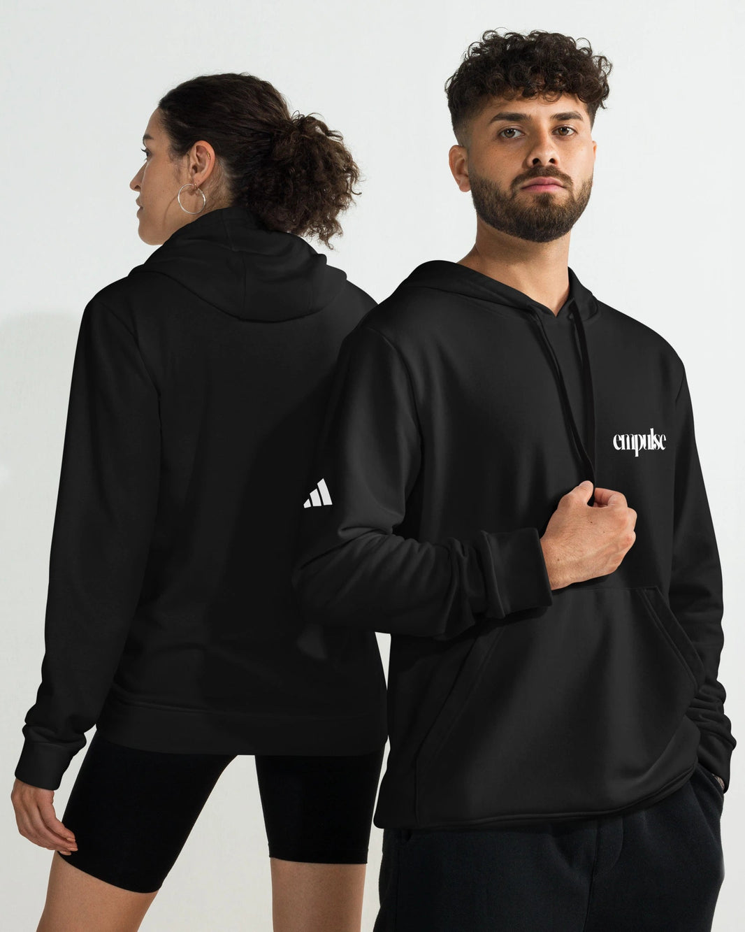 Two people wearing Adidas black hoodies with visible branding against a white background