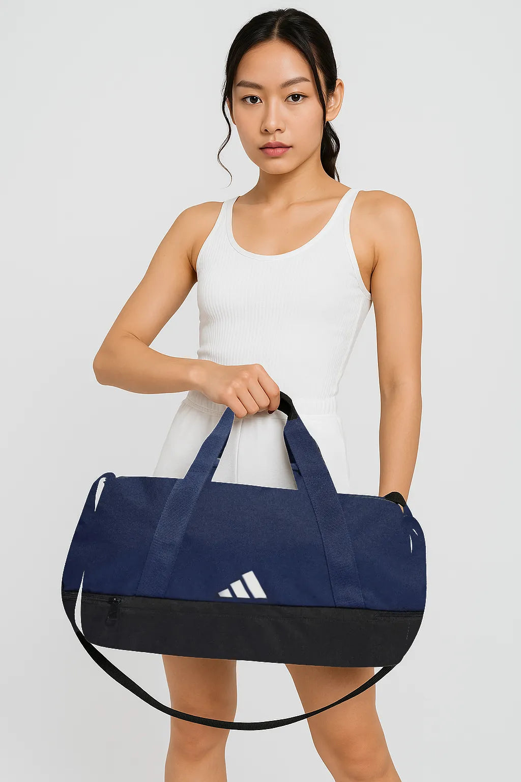 Woman holding navy blue Adidas duffel bag in front pose