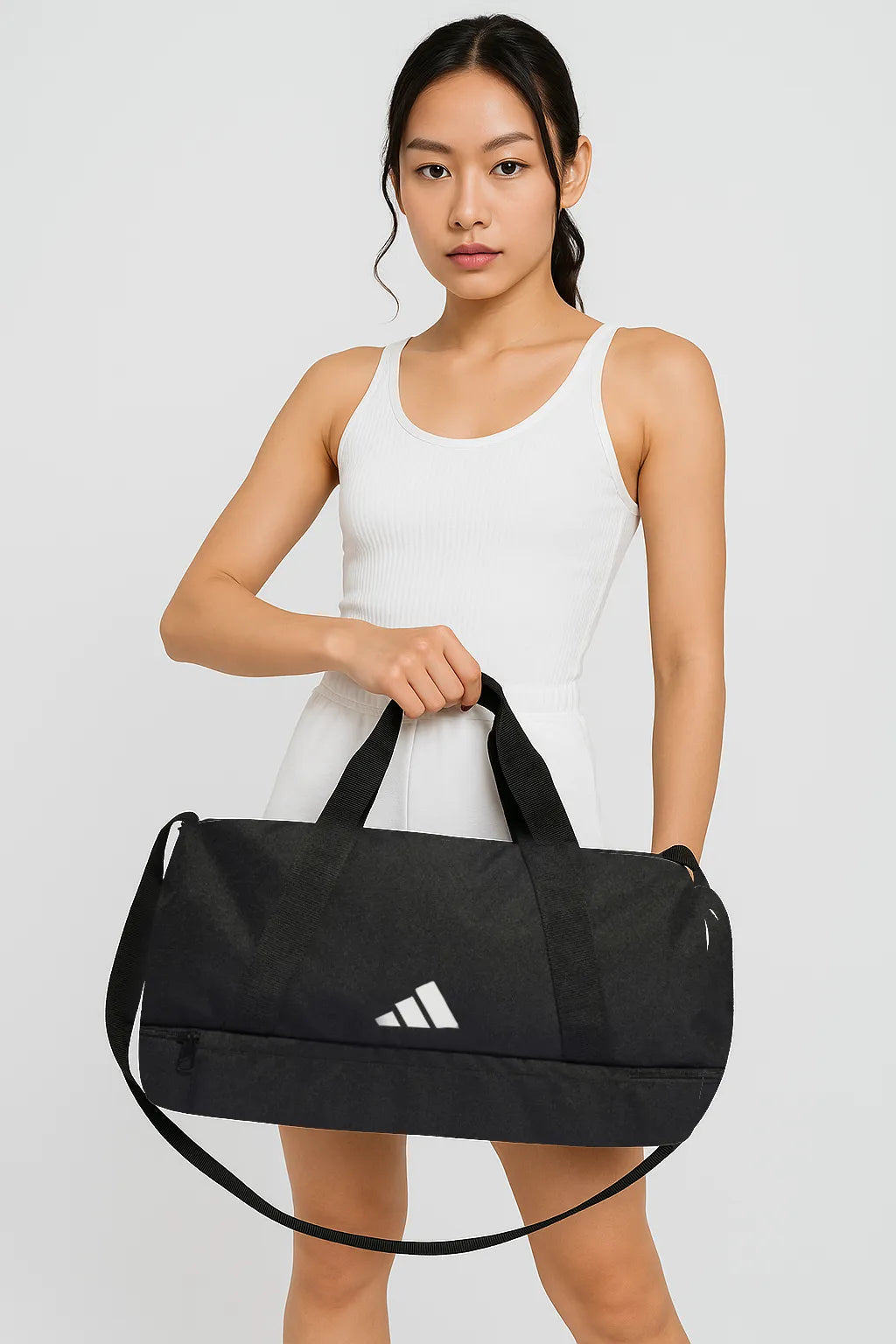 Woman wearing white dress holding black Adidas duffel bag with handles