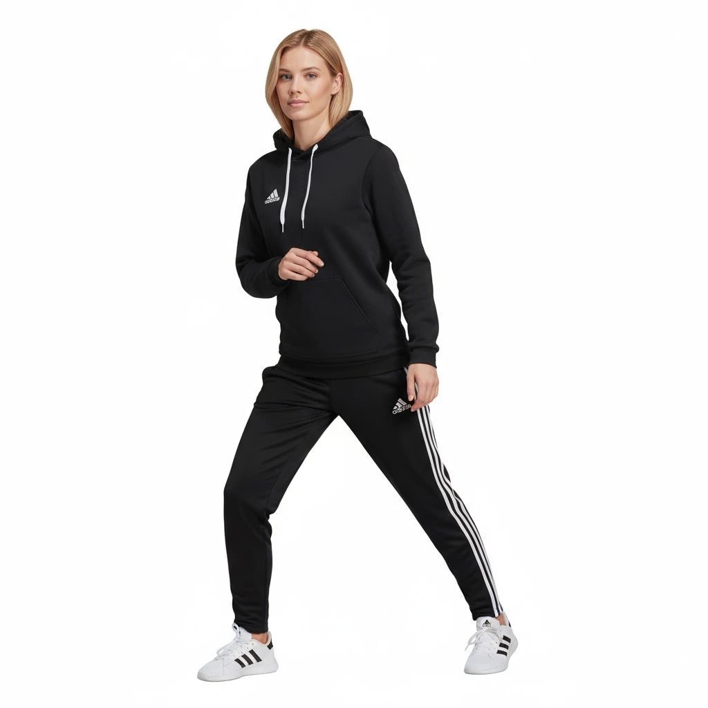 Woman wearing a black Adidas tracksuit with white stripes on a white background