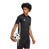 Person wearing an Adidas black sports outfit holding a soccer ball on a white background