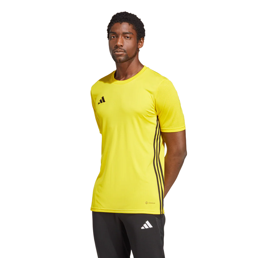 Person wearing a yellow Adidas sports shirt with black stripes on a white background
