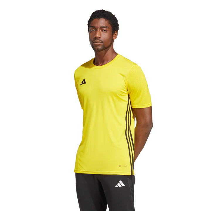 Person wearing a yellow Adidas sports shirt with black stripes on a white background