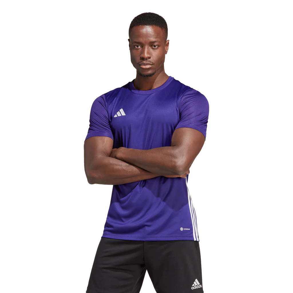 Man wearing a purple Adidas sports shirt with arms crossed on a white background