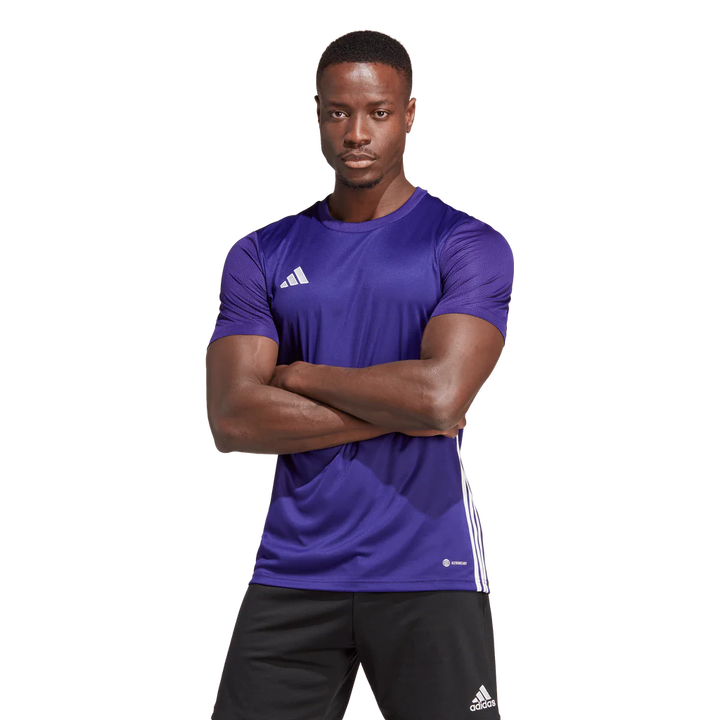 Man wearing a purple Adidas sports shirt with arms crossed on a white background