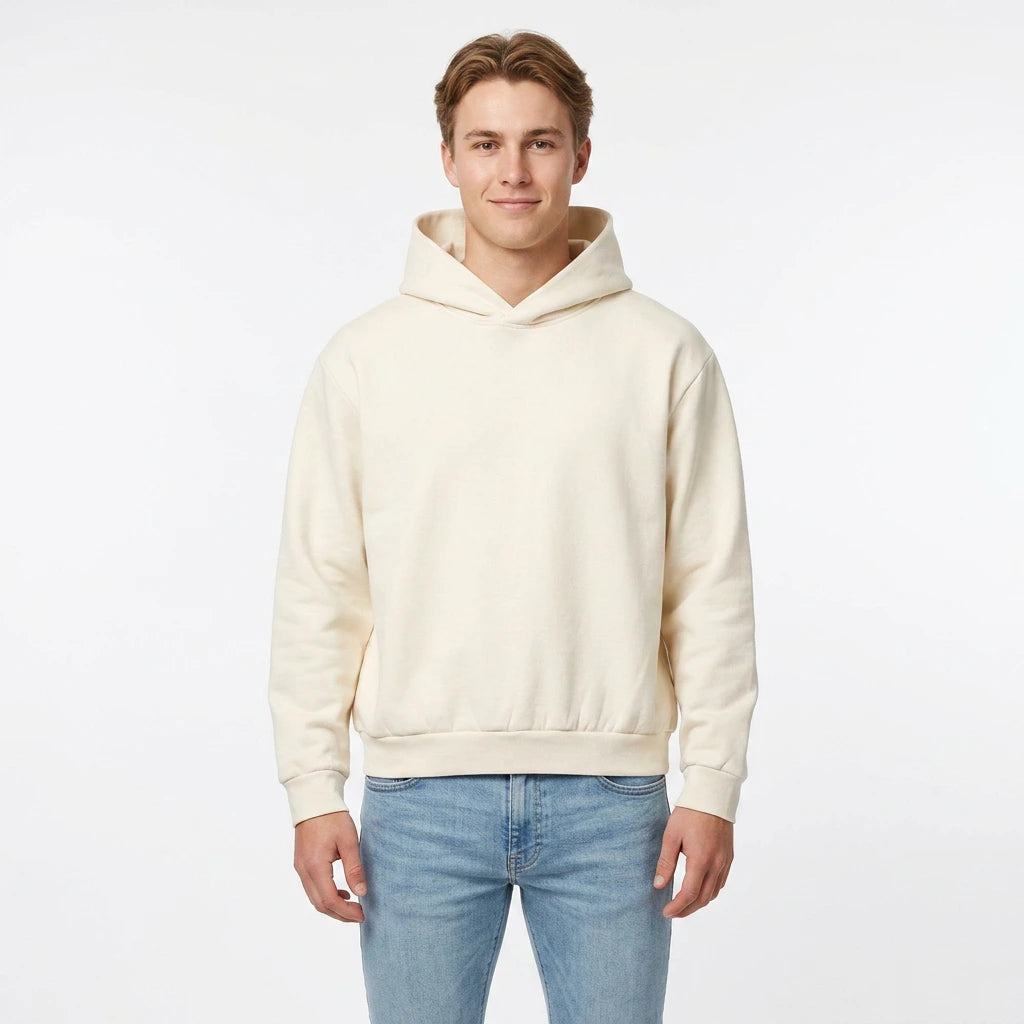 Man wearing a cream hoodie and light blue jeans on a white background
