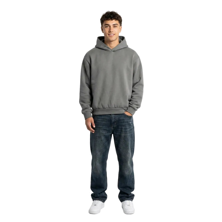 Person wearing a gray hoodie and blue jeans on a white background