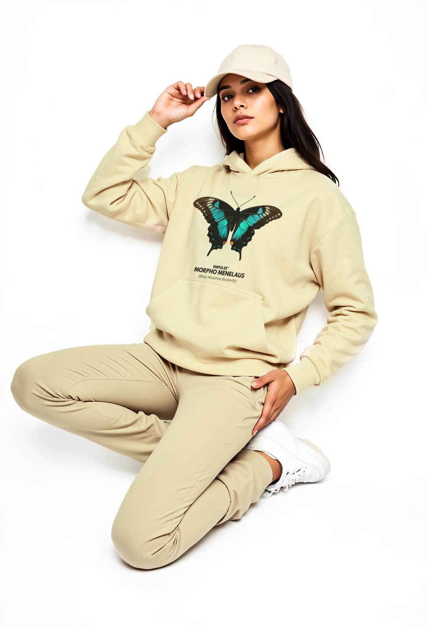 Model sitting in Empulse™ beige hoodie with butterfly artwork and casual styling