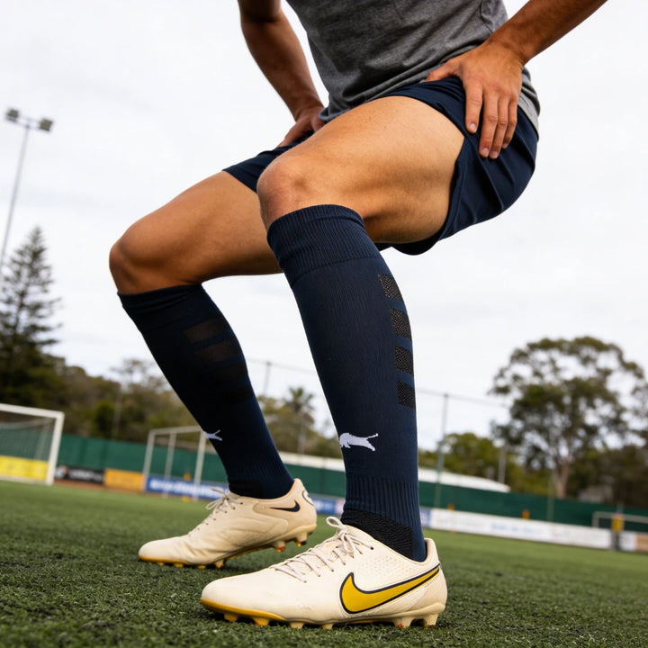 Person wearing soccer cleats with an Empulse El Toro Compression Socks on a sports field