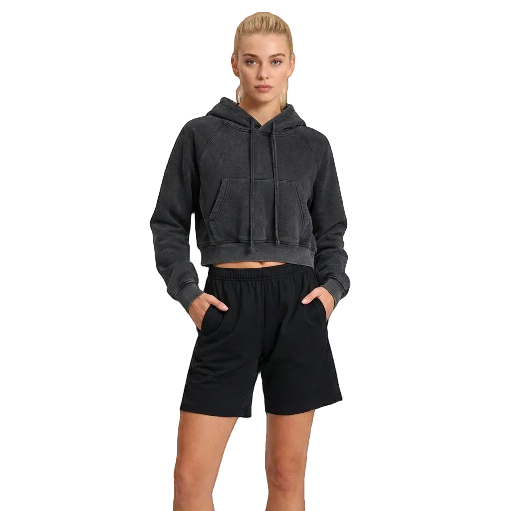 A female model wearing a dark gray hoodie and black shorts on a white background