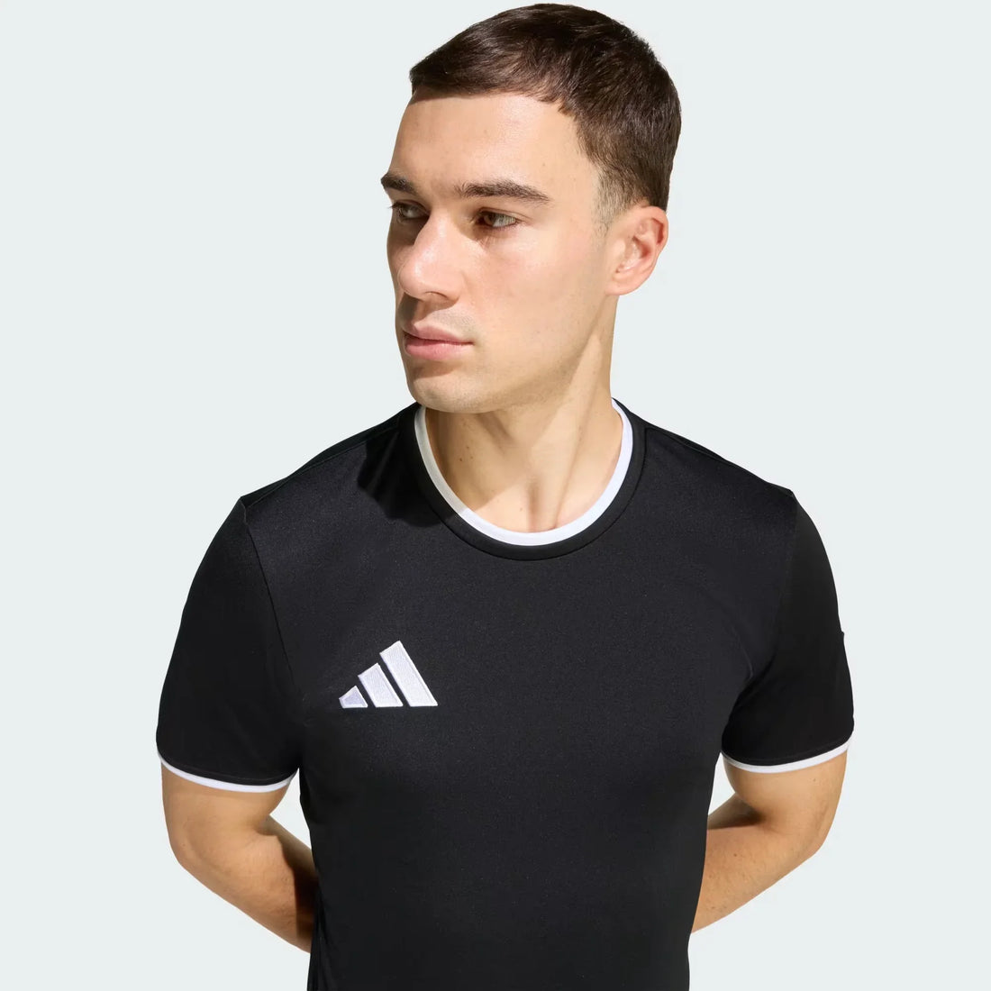 Man wearing black streetwear jersey with white trim and logo on chest