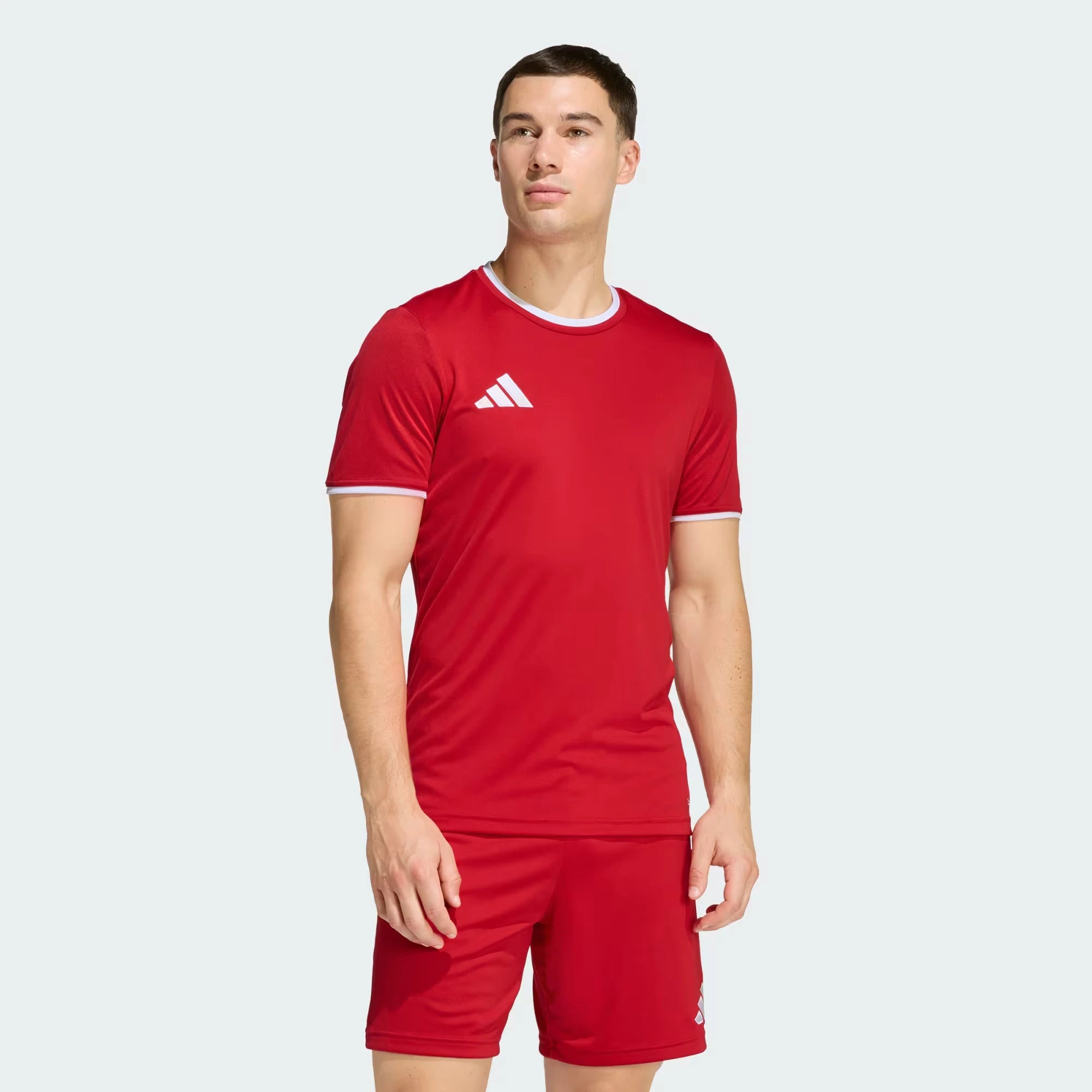 Person wearing a red sports outfit with a white logo on a light gray background
