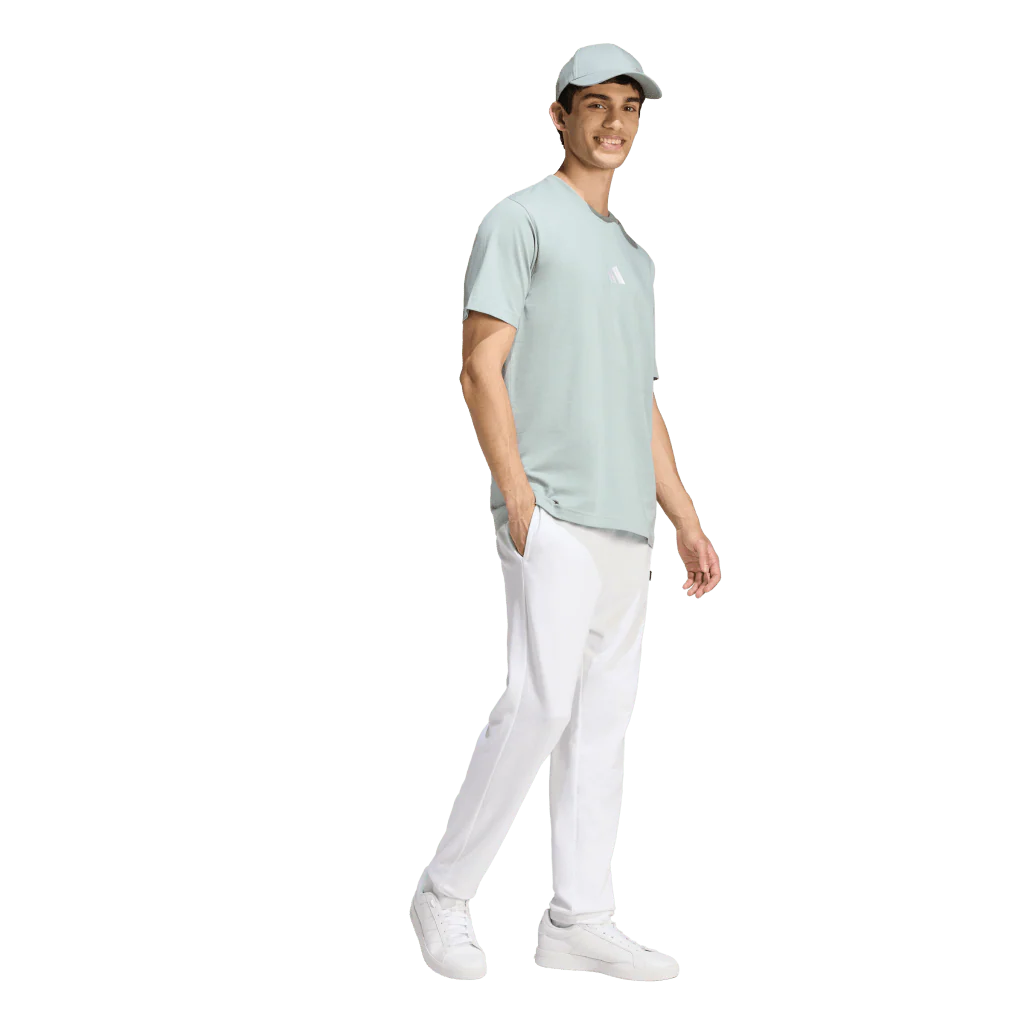 Man wearing a light green t-shirt, white pants, and a cap on a white background