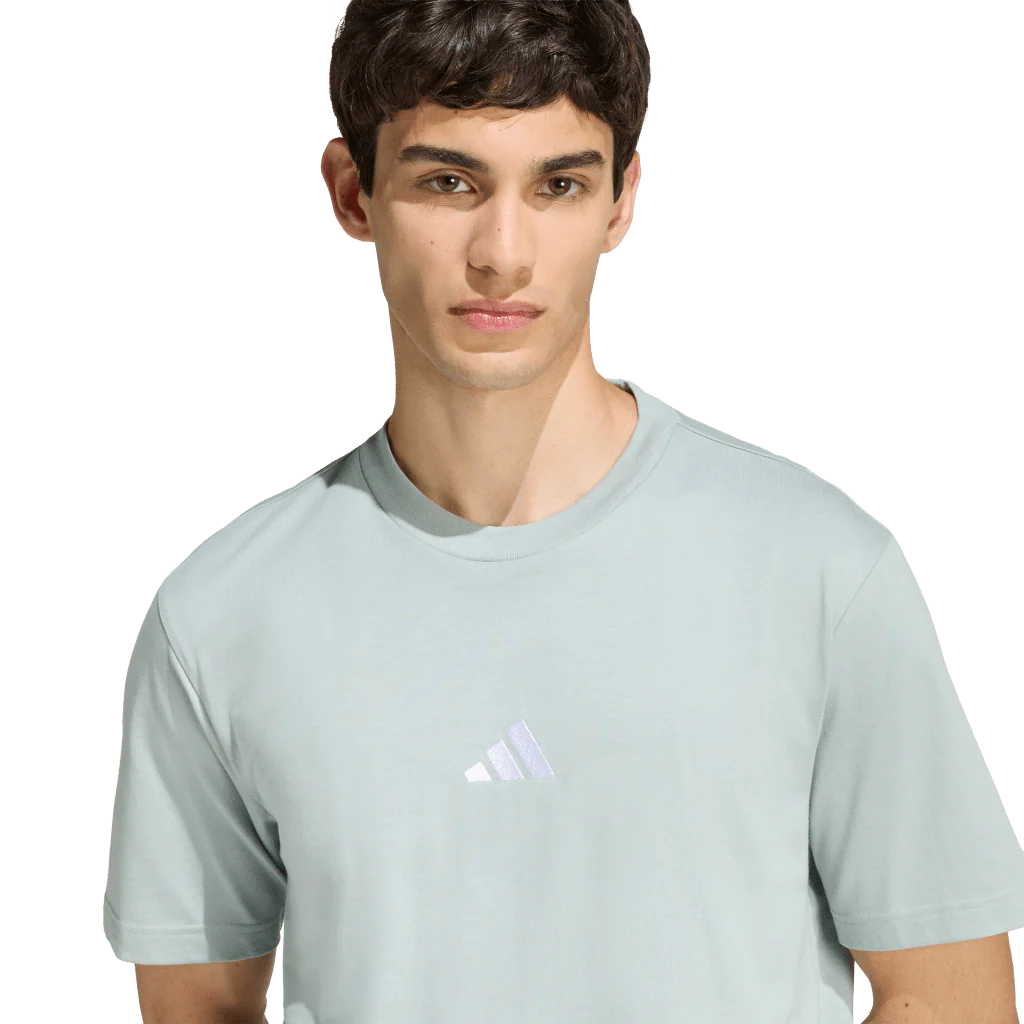 Person wearing a light blue Adidas t-shirt on a white background