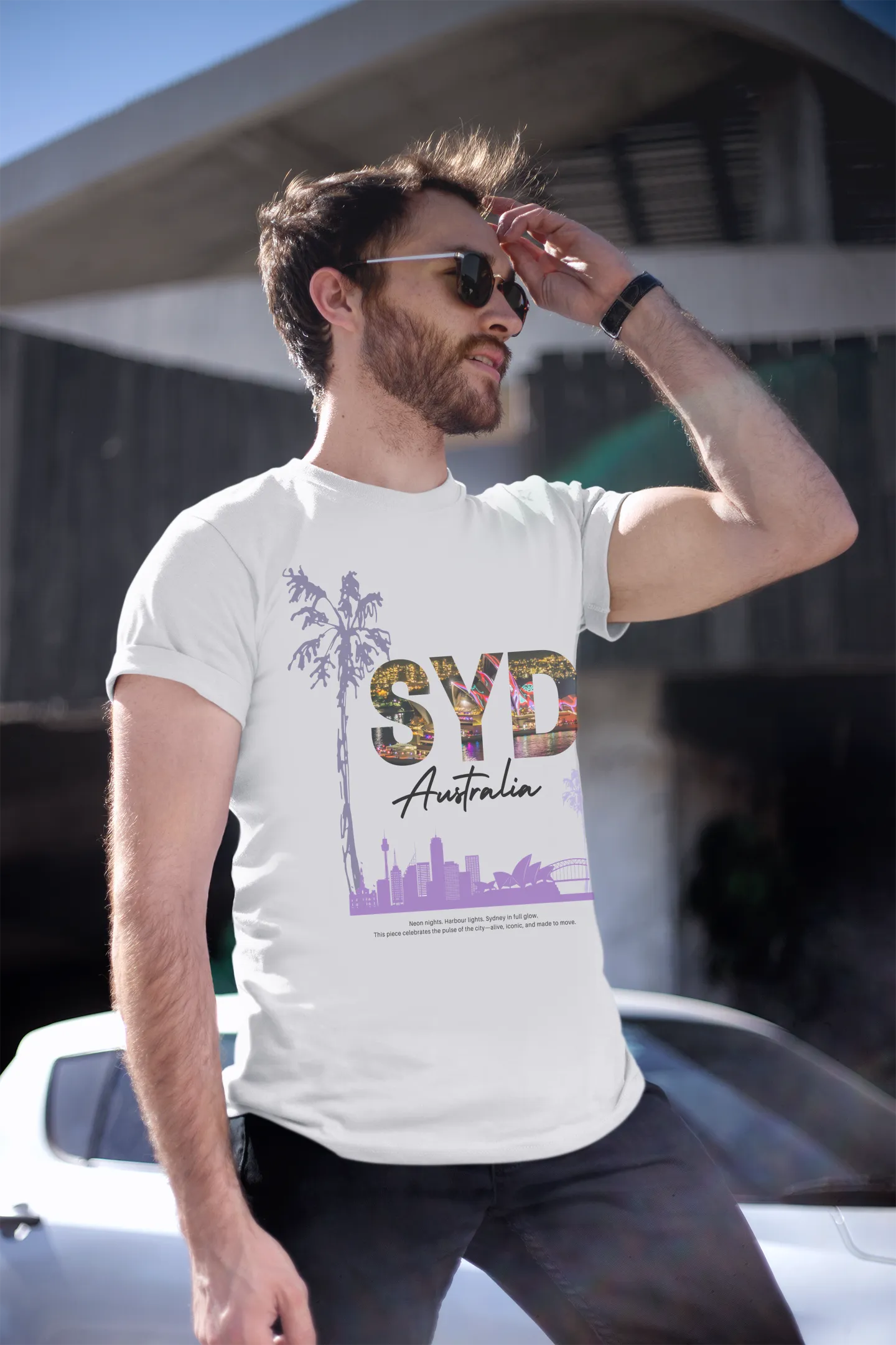 Man standing outdoors wearing Empulse™ Sydney skyline white tshirt with palm trees and purple cityscape