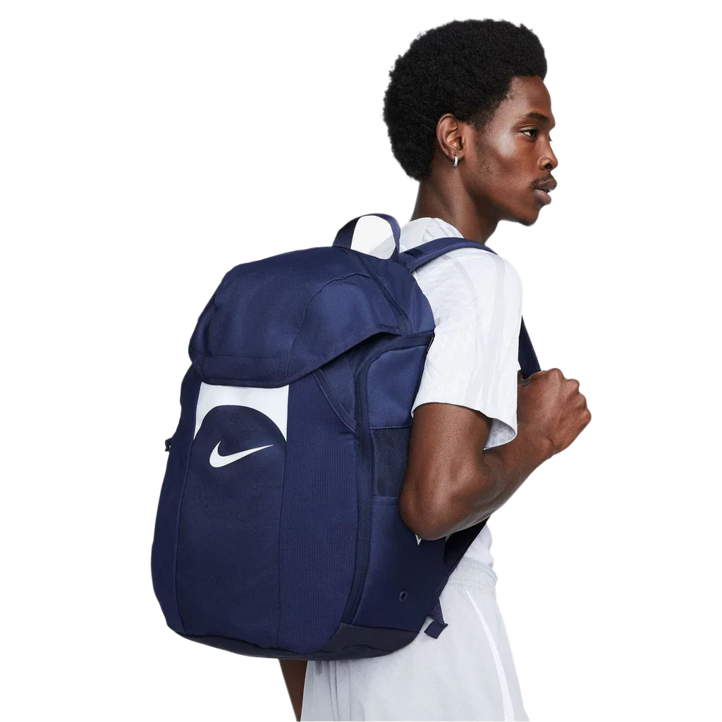 Person wearing a navy blue backpack with a white logo on a white background