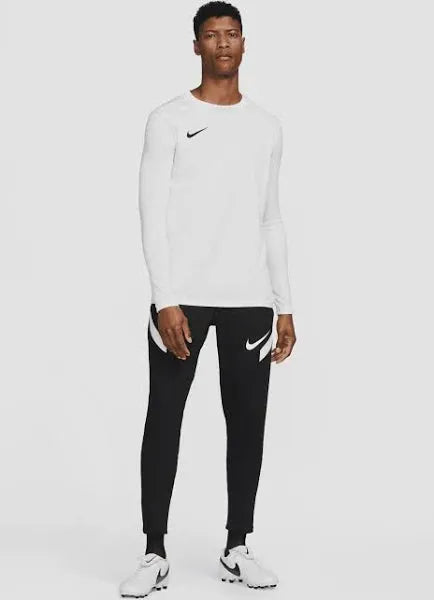 Full body view of male model wearing white Nike Park VII long sleeve top with black pants and white sneakers.