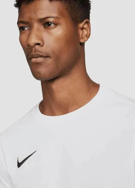 Male model in white Nike Dri-FIT Park VII long sleeve shirt with swoosh logo, close-up upper chest and face.

