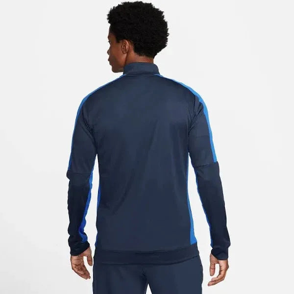 Person wearing a navy tracksuit with blue accents on a white background