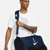 Male model carrying Nike Academy Team Duffel Bag navy with shoulder strap