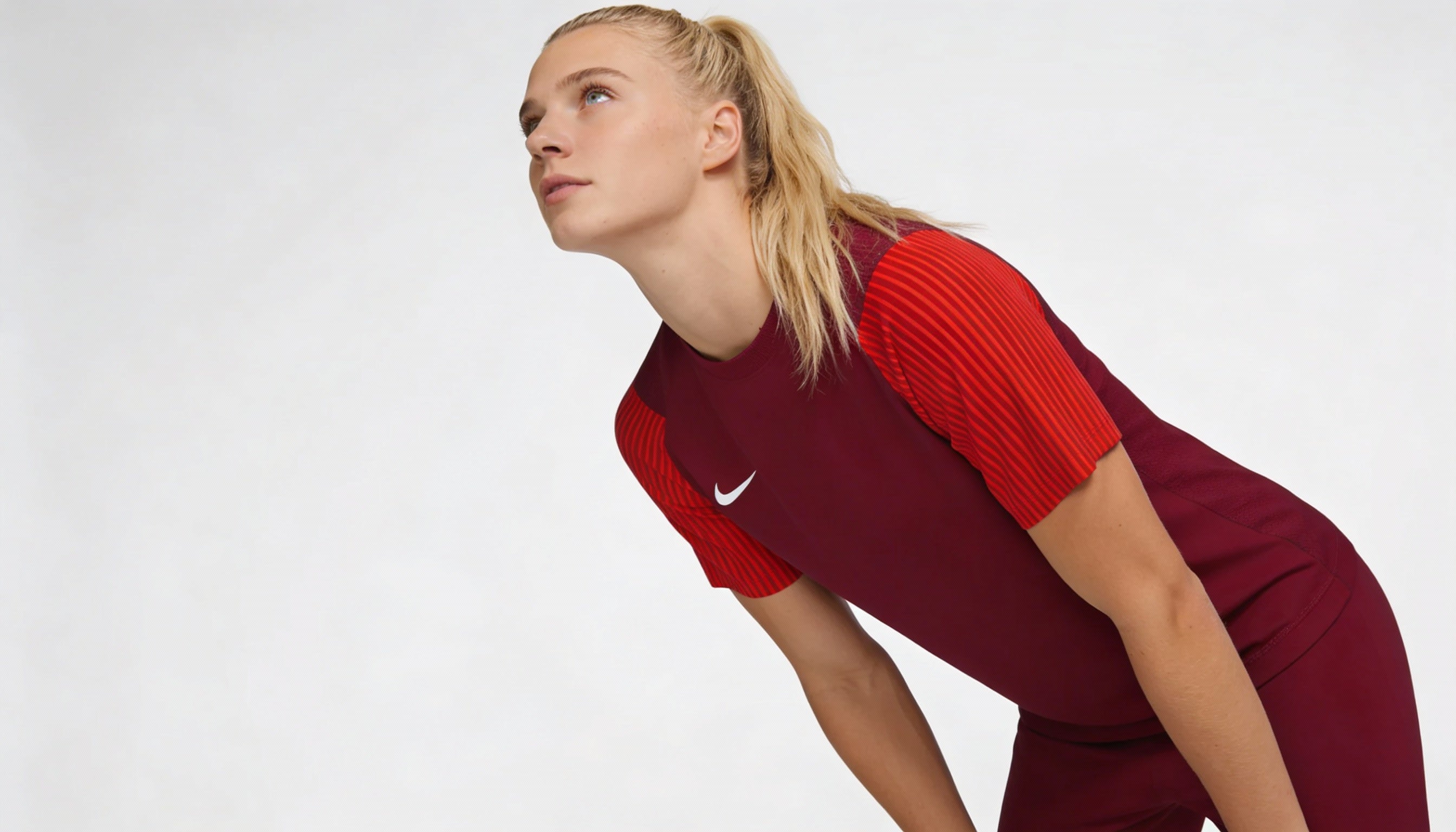 Woman wearing a red and maroon outfit with a Nike logo on a white background