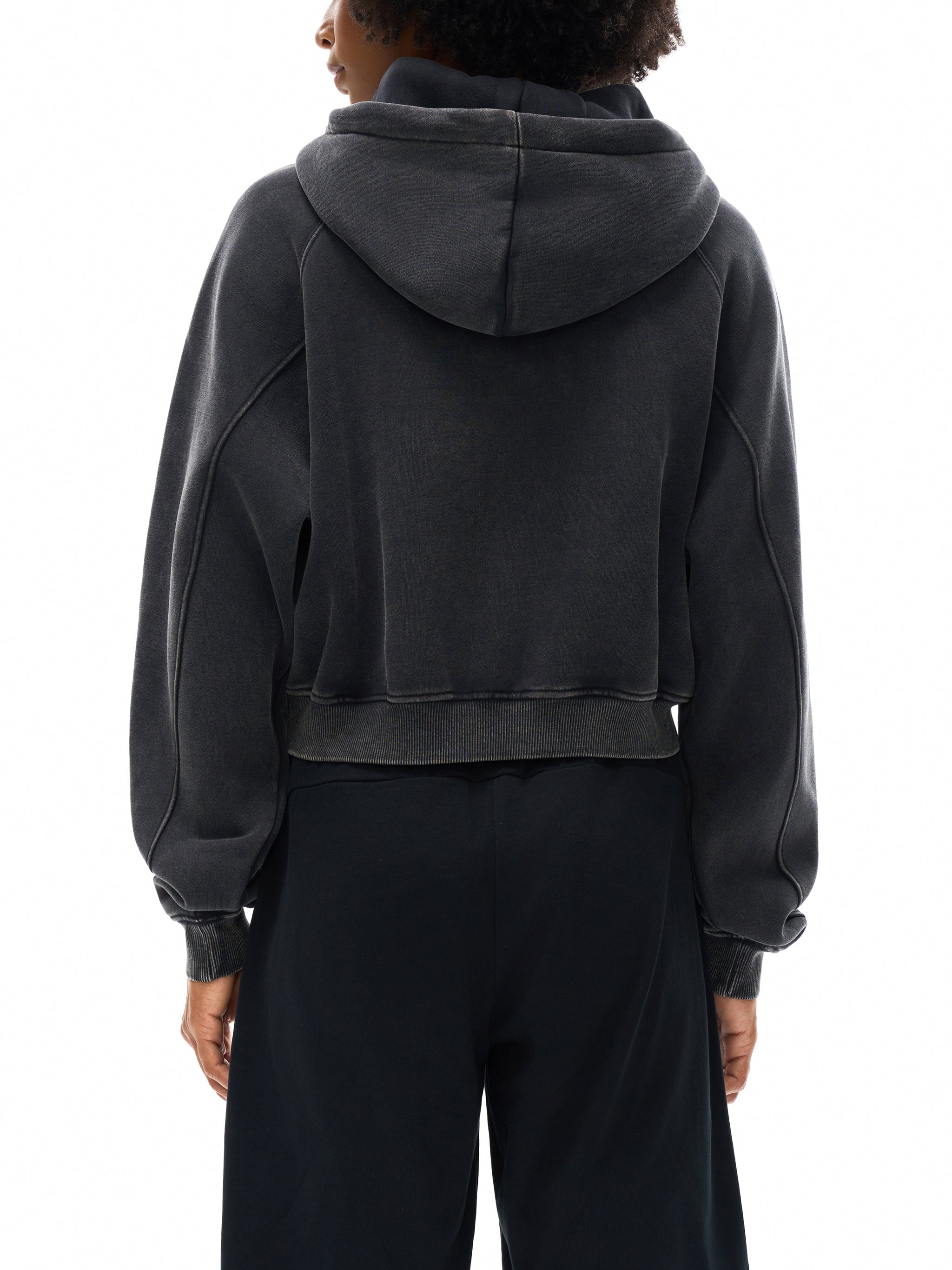 Person wearing a black hoodie and pants on a white background