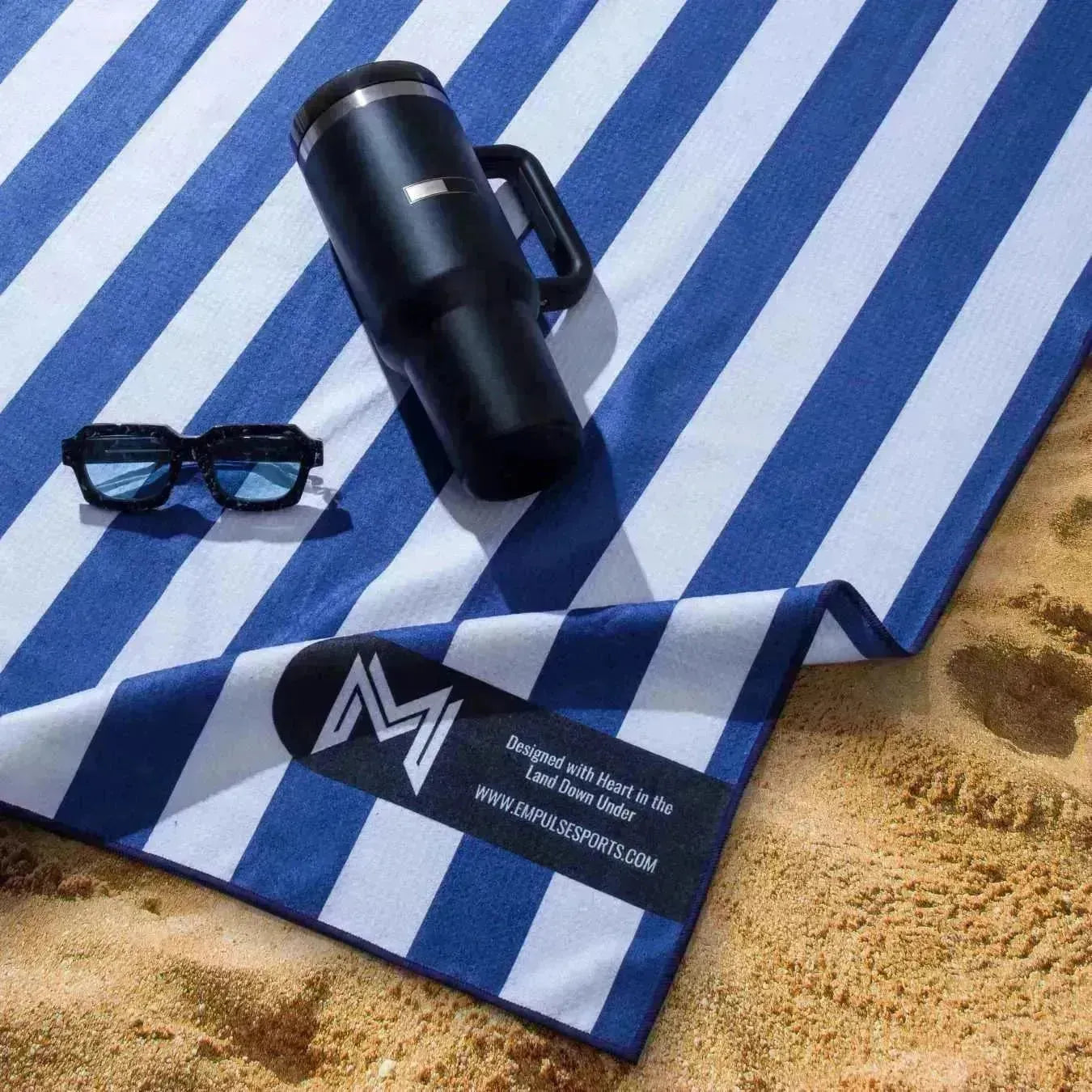 Cabana towel on sand with sunglasses and drink bottle