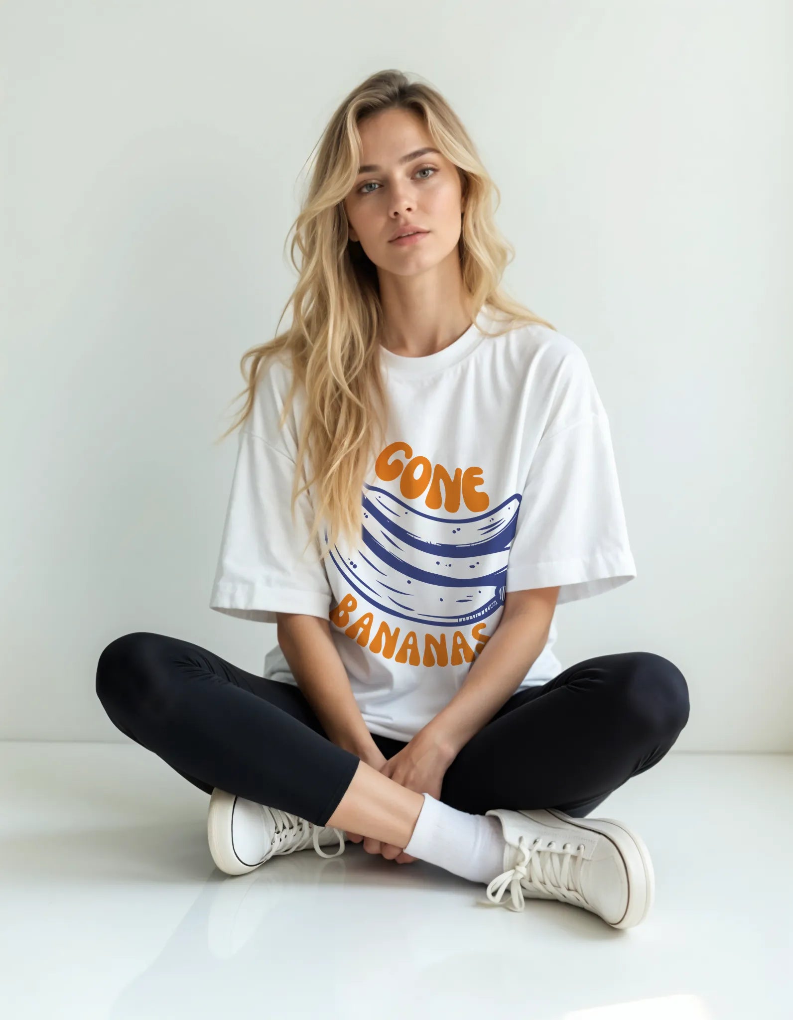 Empulse™ Banana Waves t-shirt in white Sorona blend with retro wave banana print, worn by female model seated