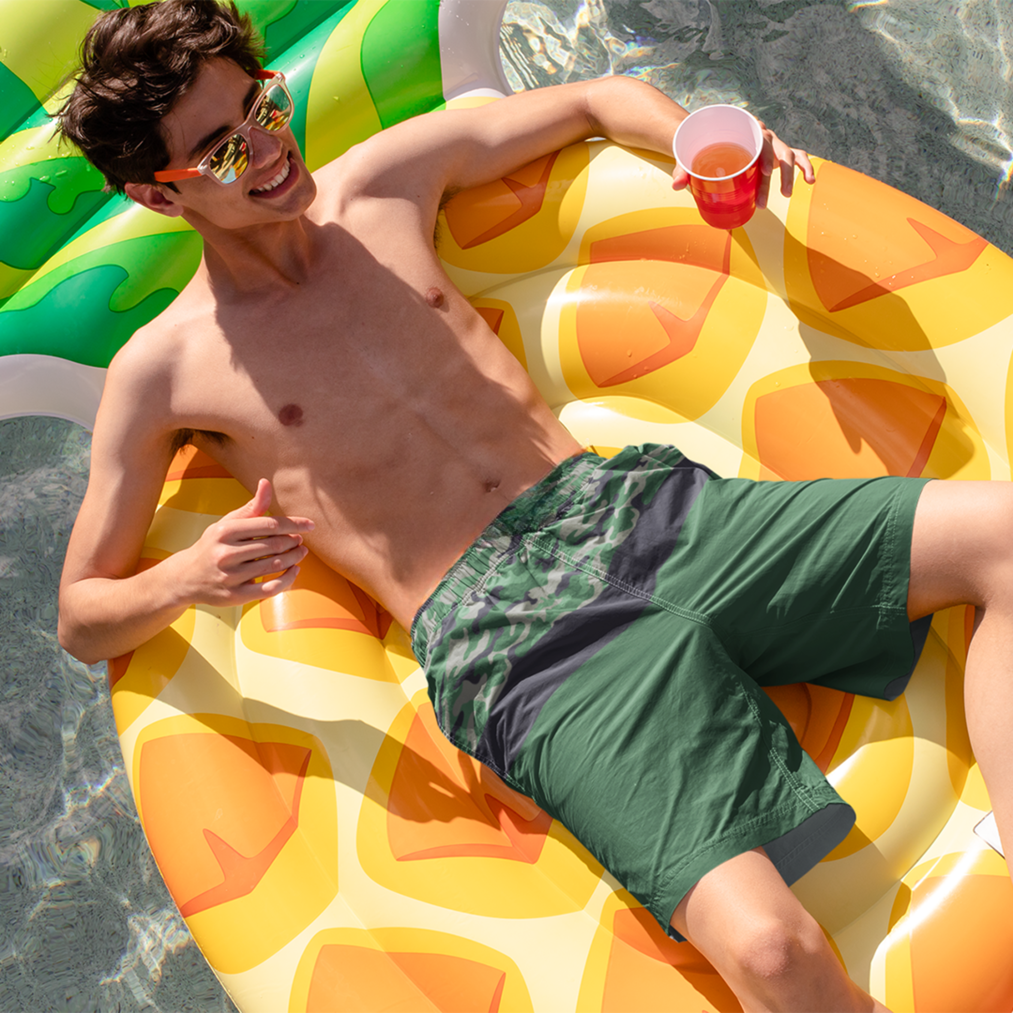 Model lounging in Empulse™ Camouflage shorts on inflatable pool float in the sun