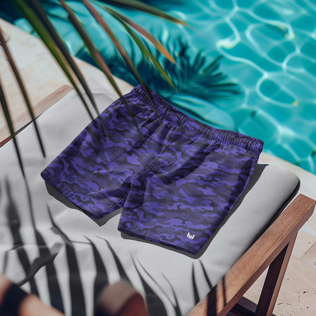 Flat lay of Empulse™ Cobalt Camouflage swim shorts displayed on lounge chair near pool
