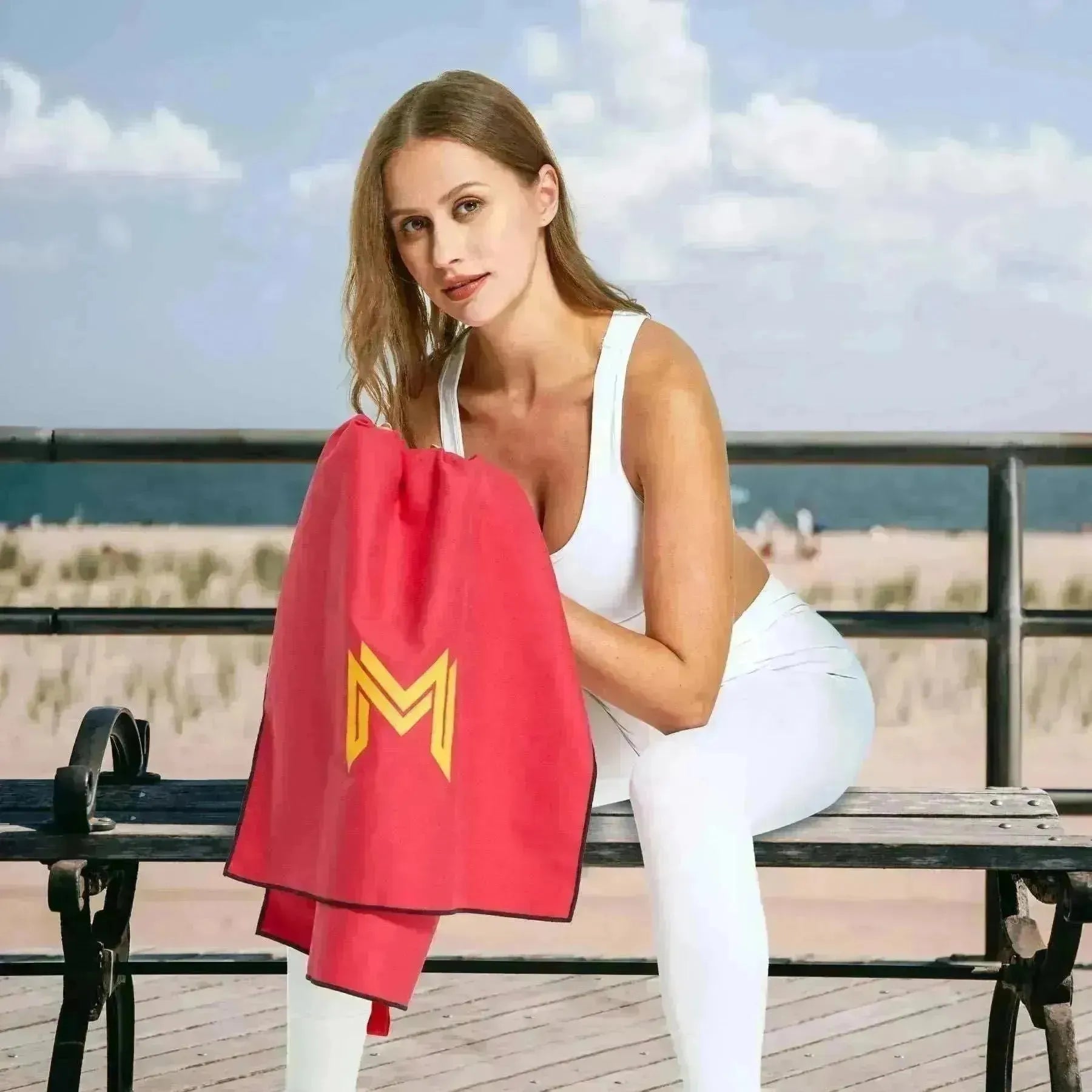 Model seated outdoors post-gym with Empulse™ Crimson Core towel around neck
