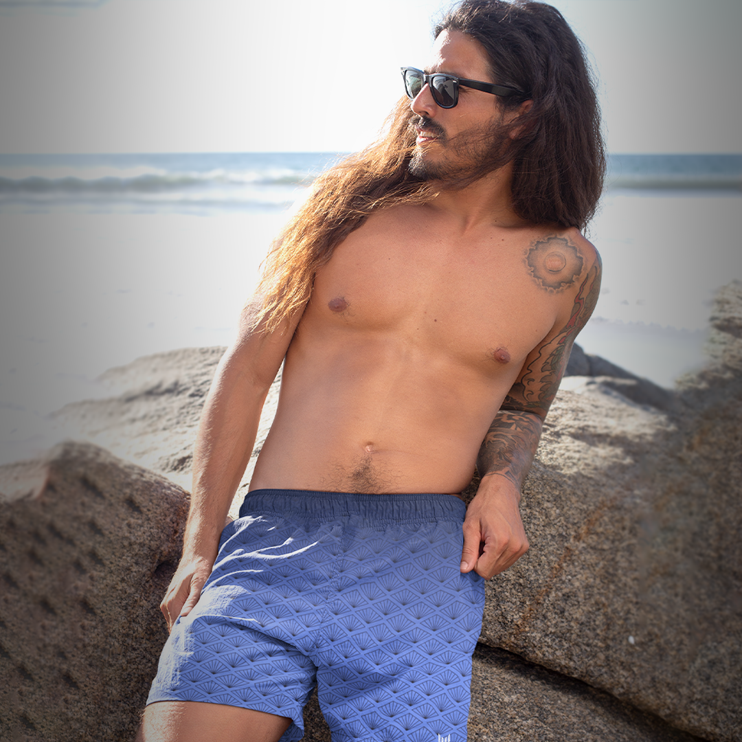 Tattooed model wearing Empulse™ Daylight Bloom shorts in relaxed beach pose