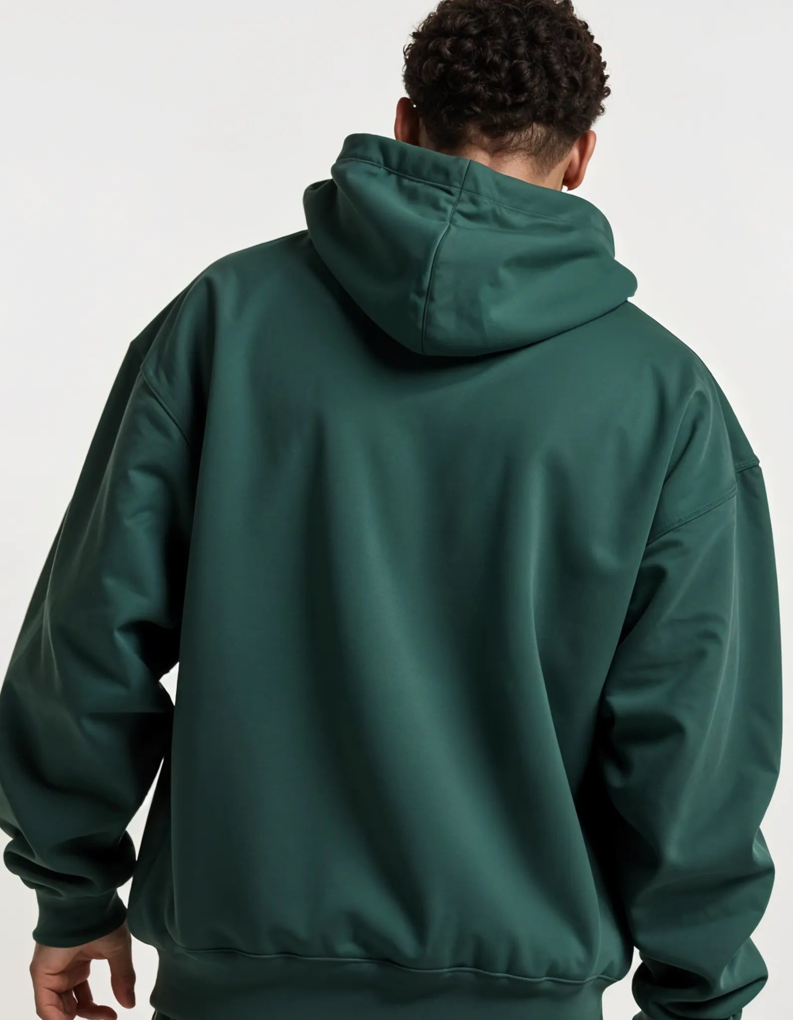 Male model sitting in forest green Empulse DNA Oversized Hoodie and matching pants