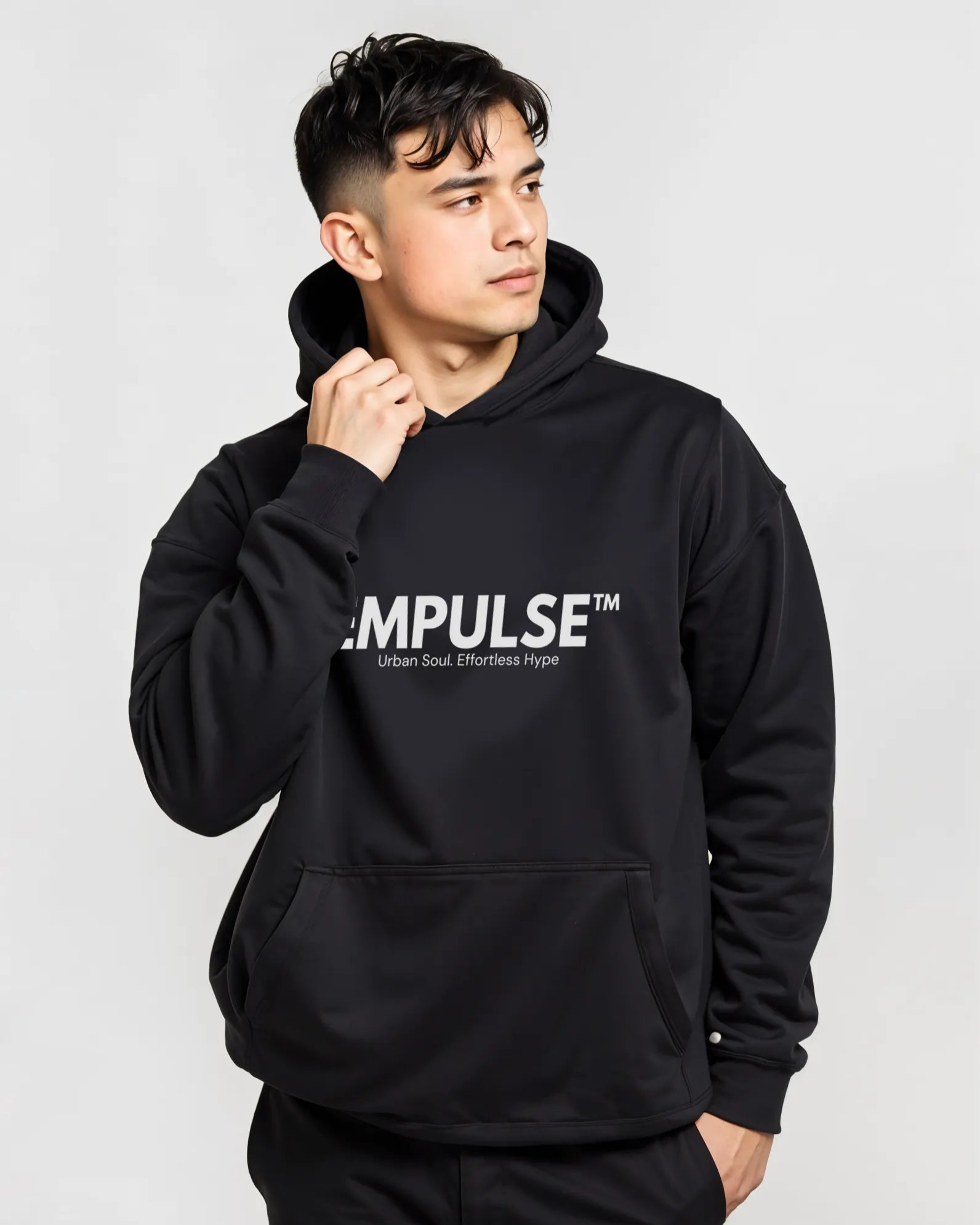 Young man in Empulse™ hoodie glancing sideways with casual styling in minimalist studio

