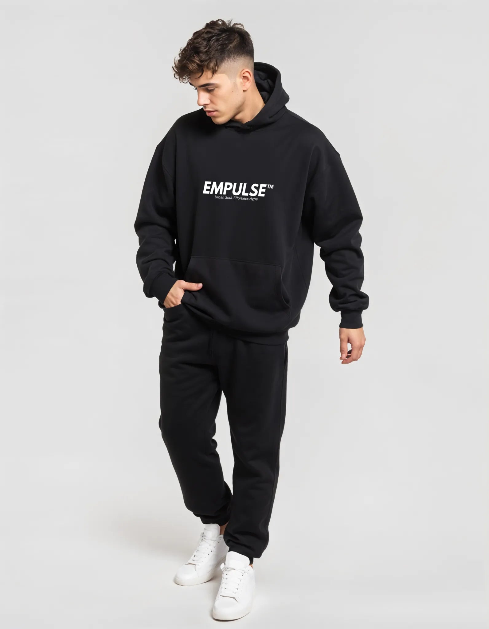 Full-length view of man walking in Empulse™ logo hoodie and joggers, studio-lit profile