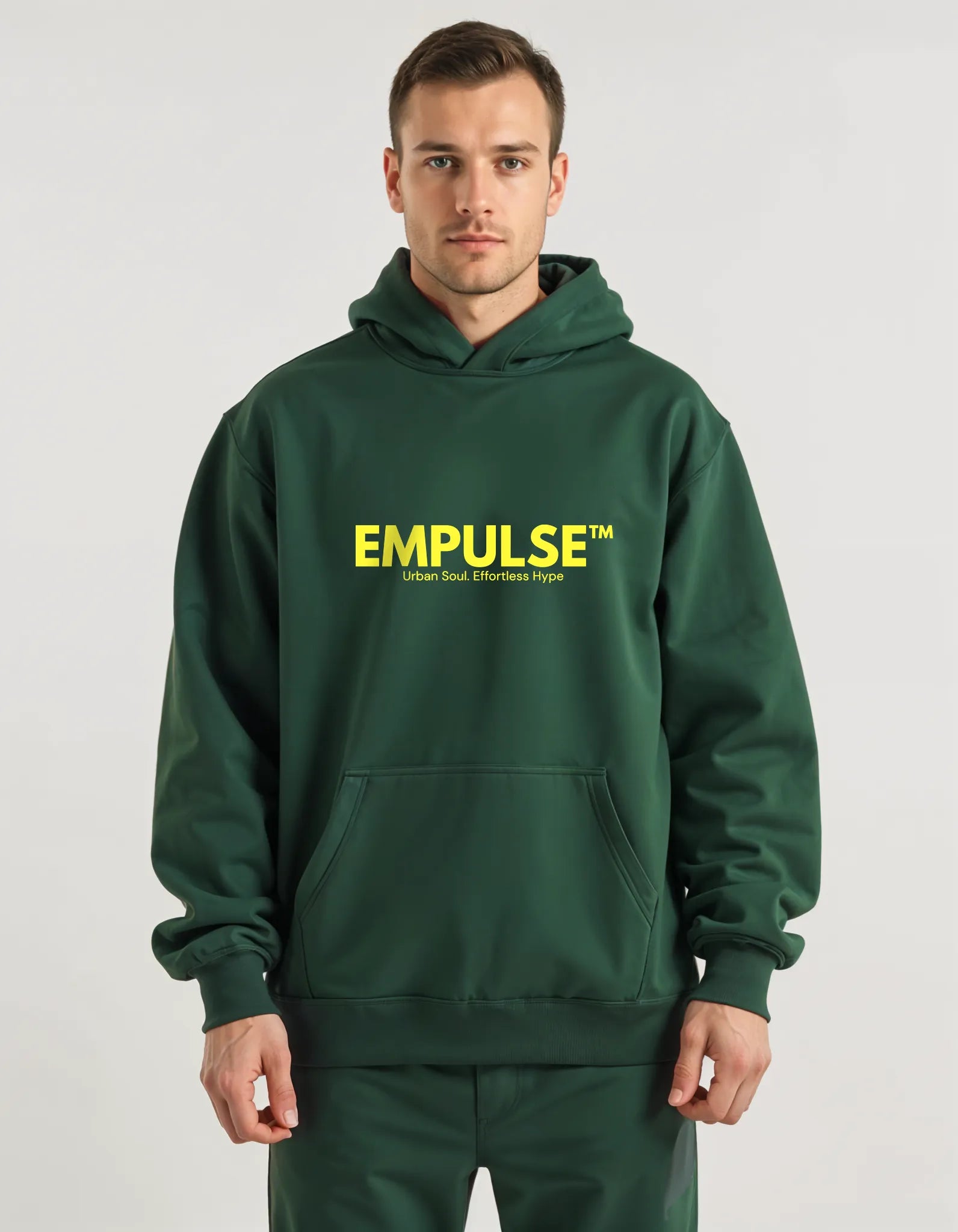 Male model wearing Empulse™ forest green hoodie with bold yellow logo, studio front view