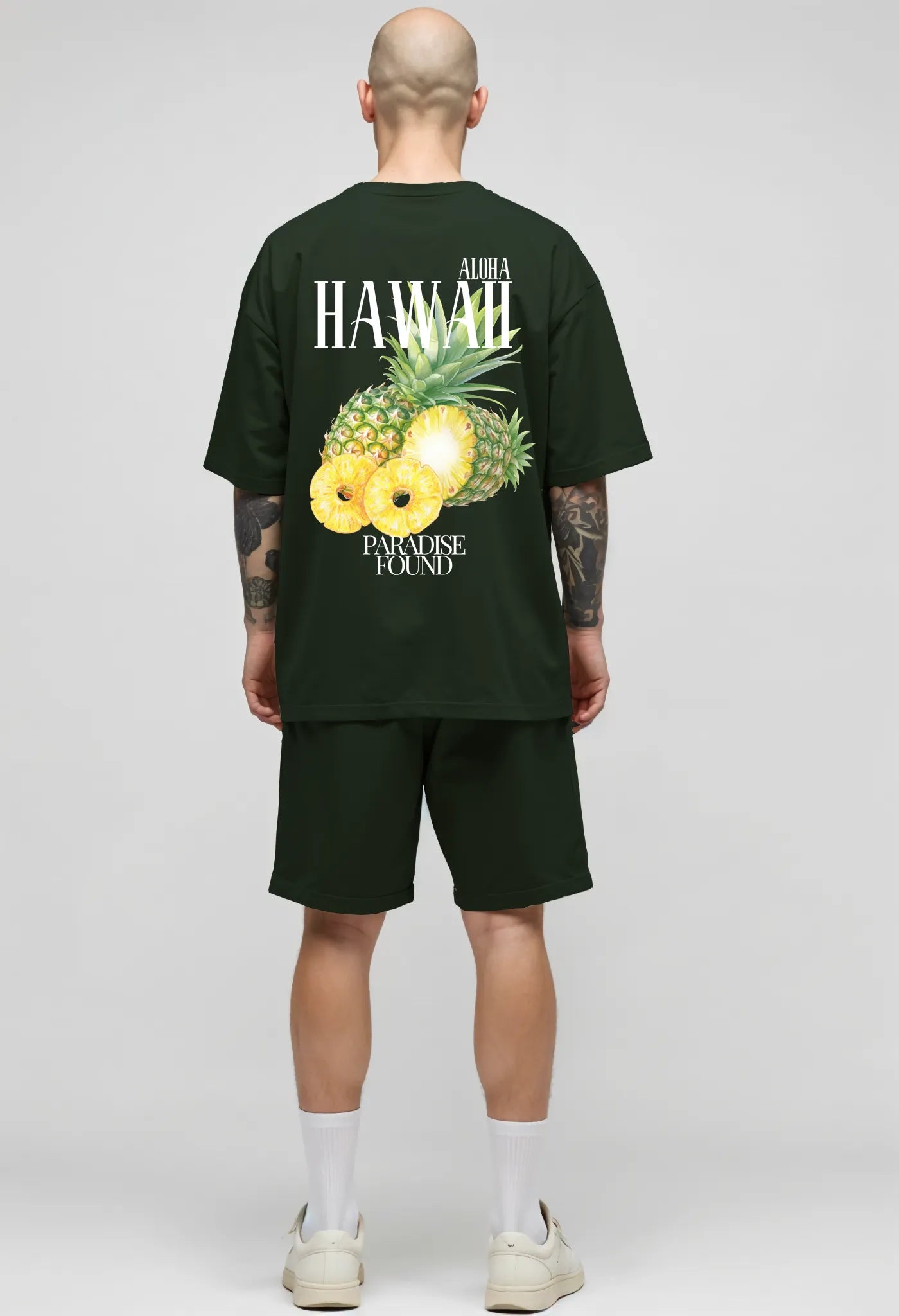 Full-body view of Empulse™ green Hawaii Sorona tee with pineapple print, worn with black shorts