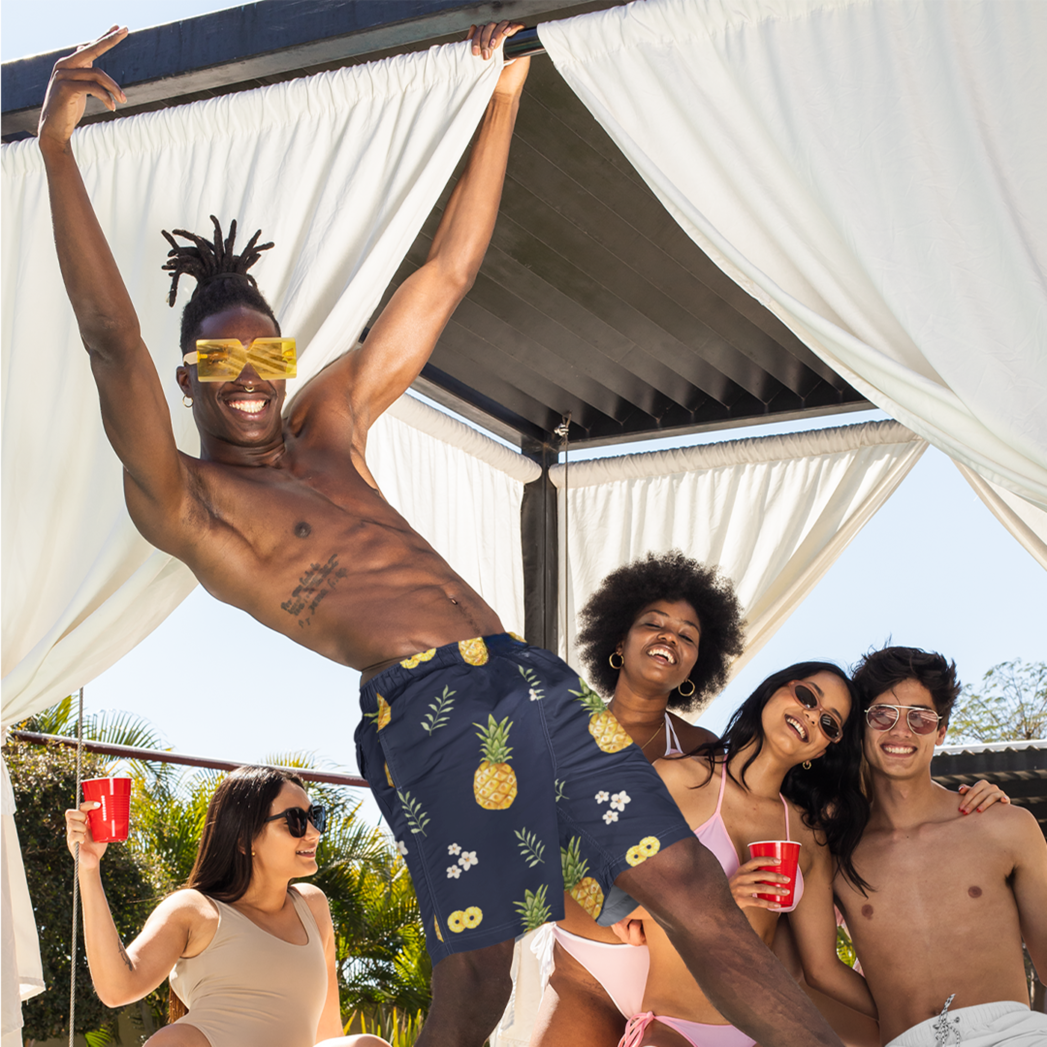 Group of friends celebrating while one wears Empulse™ Pineapple Paradise swim shorts