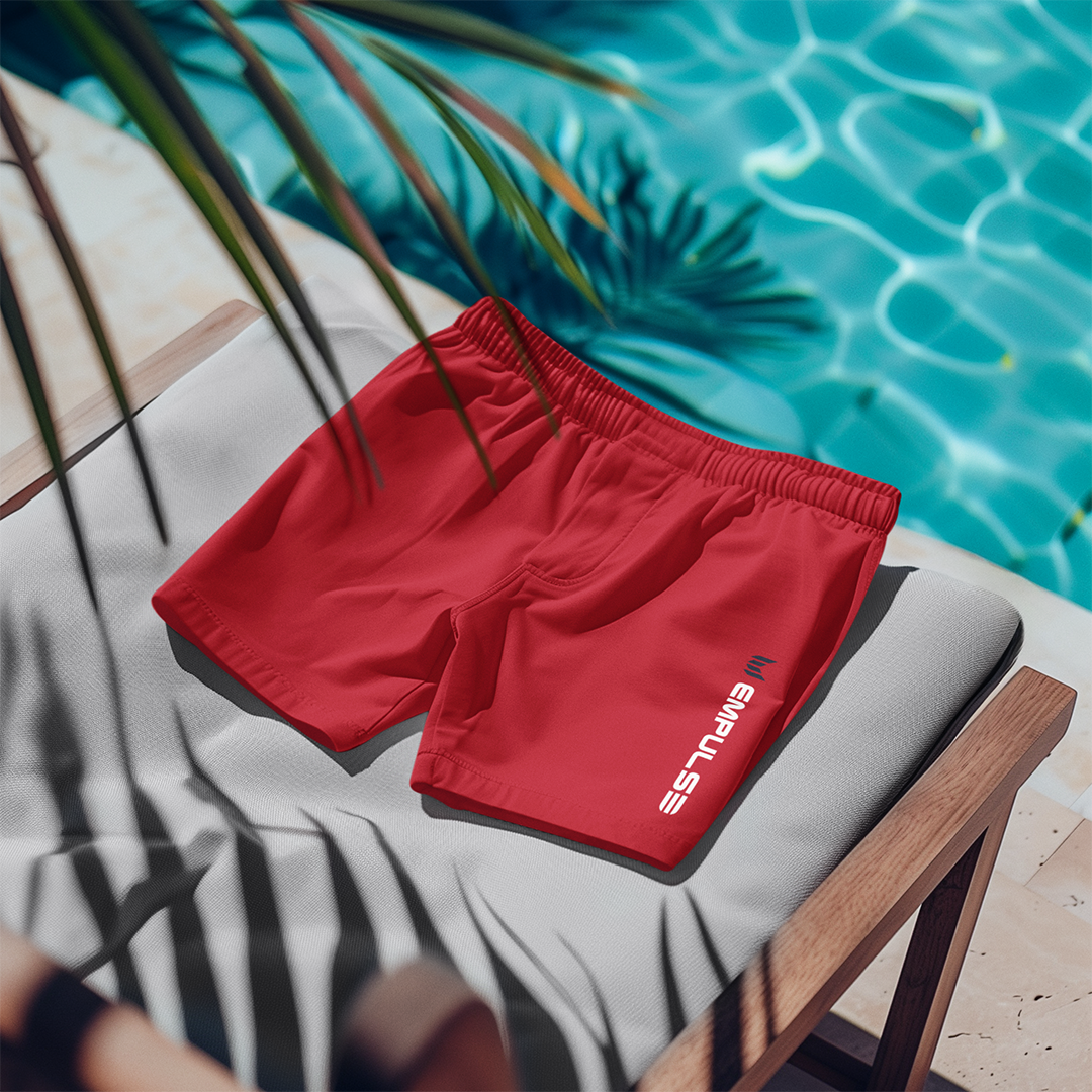 Empulse™ Red swim shorts folded neatly on outdoor lounge chair beside the pool