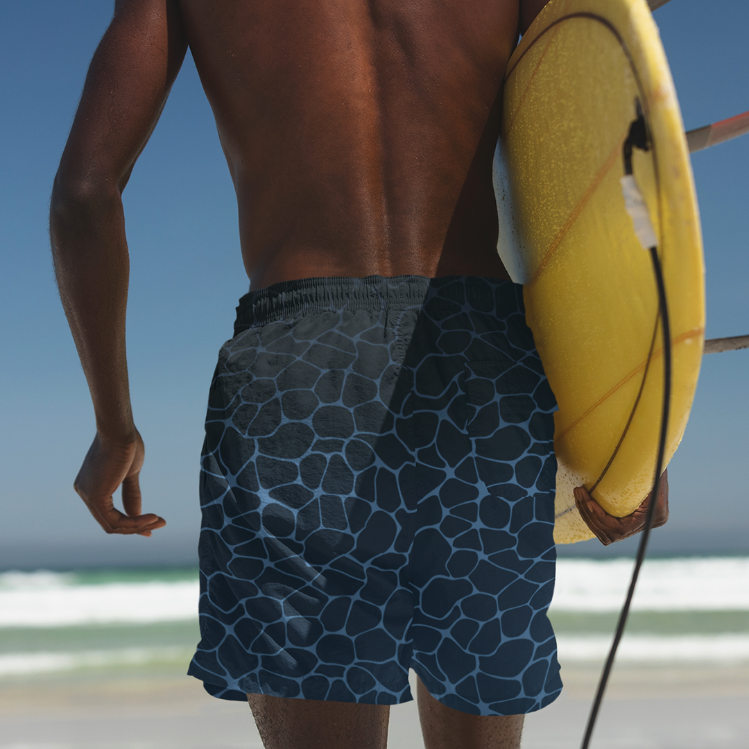Empulse™ Ripple Magic swim shorts worn at the beach with a surfboard in hand
