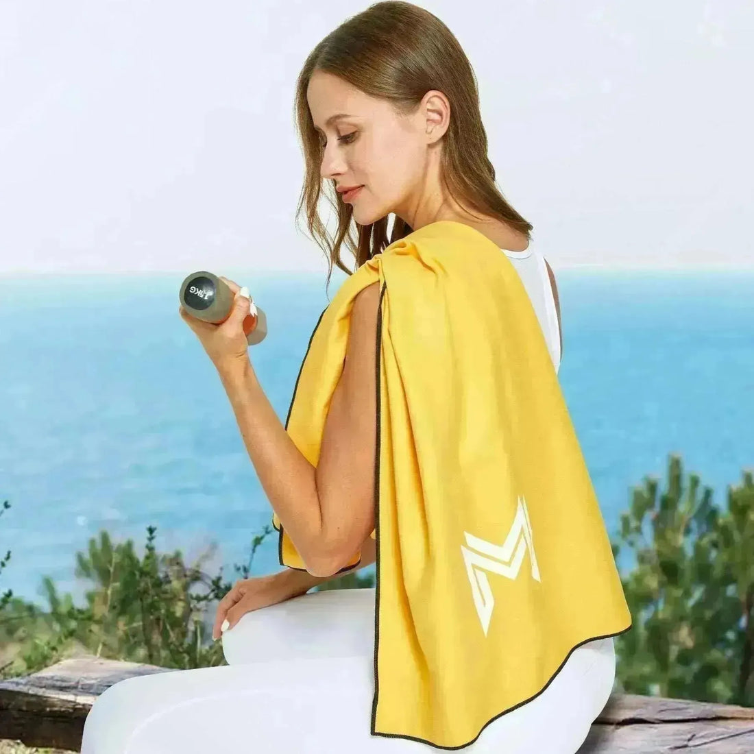 Empulse™ Sunrise Splash towel draped around shoulders with dumbbell and ocean in background