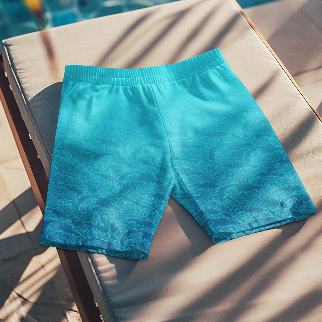 Flat lay of Empulse™ Turquoise Tides swim shorts on a striped beach chair in the sun