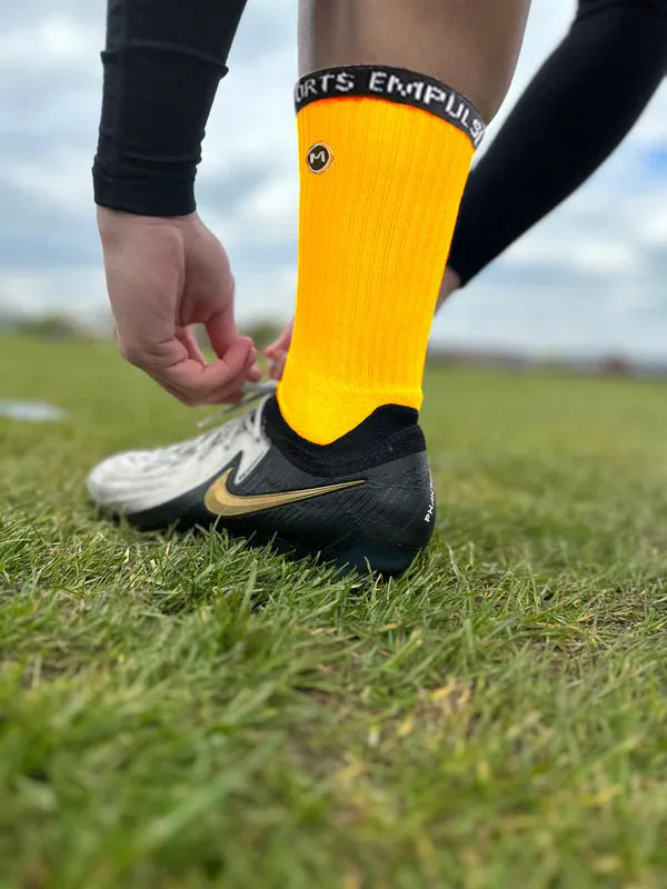 Orange grip socks worn on grass field perfect for soccer and athletic training