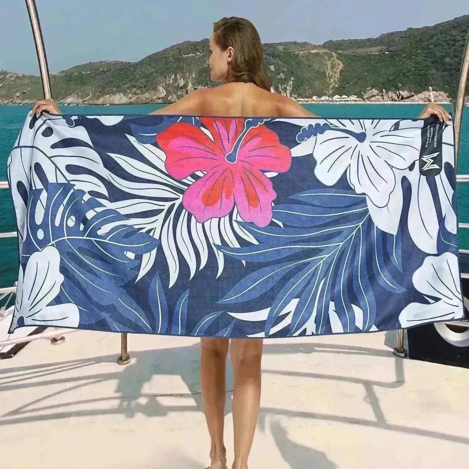 Model holding open Tropical Bloom towel with large pink flower and navy leaf print
