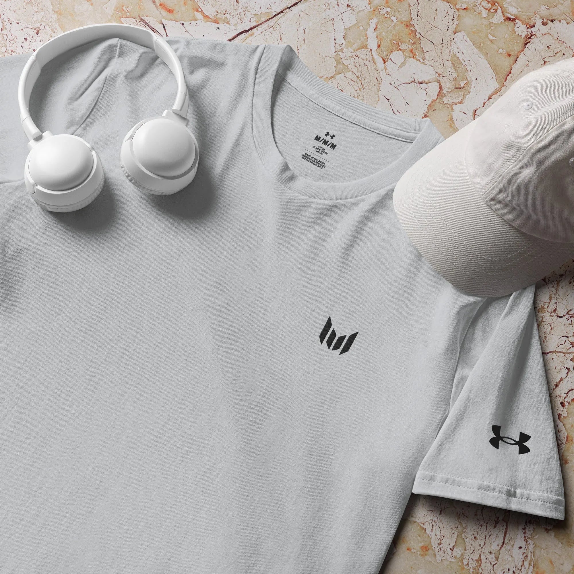 Under Armour light grey athletic tee flat lay with earbuds on top