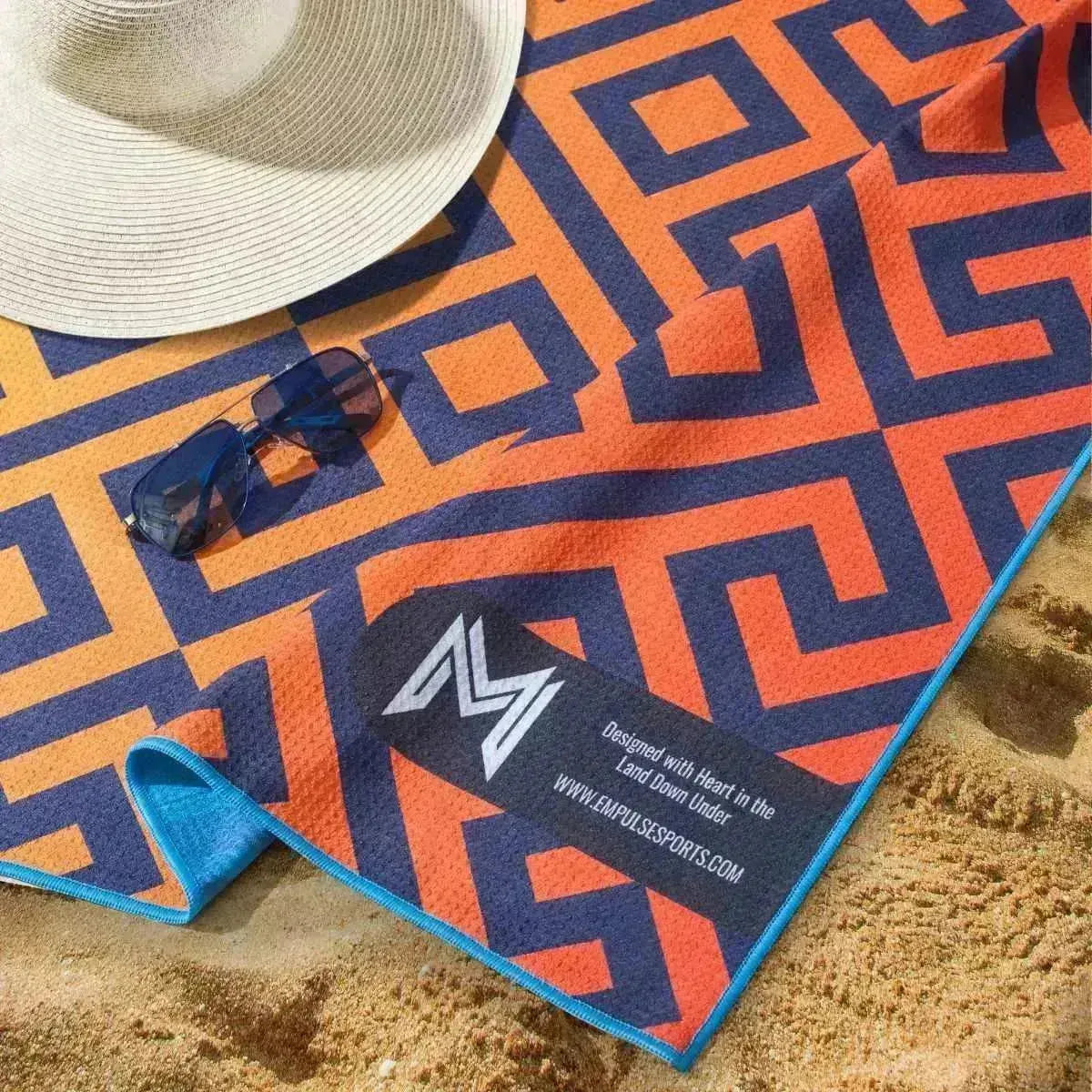 Empulse Vibrant Canopy towel laying flat on sand showing bright reverse-side print